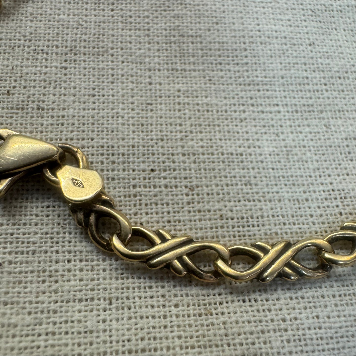 צמיד זהב צהוב 14 קראט עם חוליות שזורות בעיצוב שזירה ופיתול, וסוגר מסוג לובסטר.