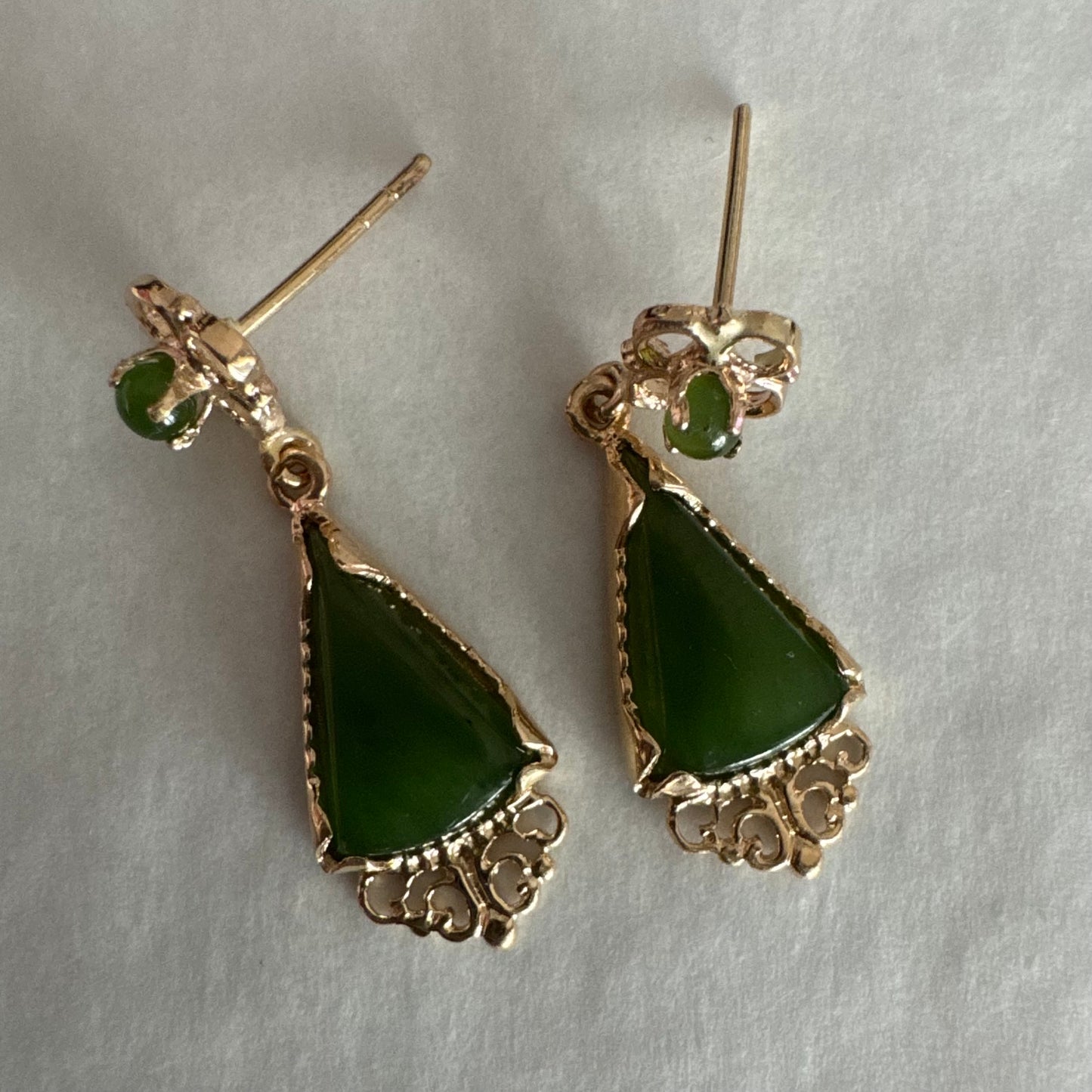 עגילי זהב צהוב 14 קראט משובצים אבני ג׳ייד ירוקות בגוון עמוק בחיתוך משולש.