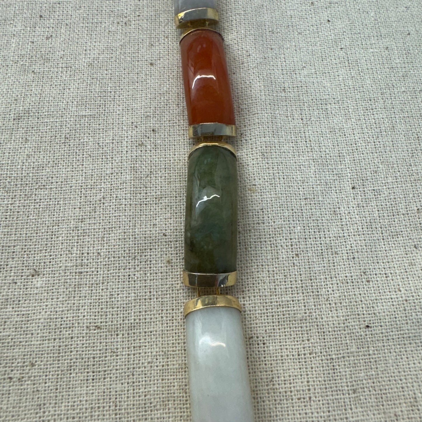 צמיד זהב צהוב 14 קראט עשוי מקטעי ג’ייד (jade) בשלושה גוונים – ירקרק, לבן ואדום – בשיבוץ זהב.