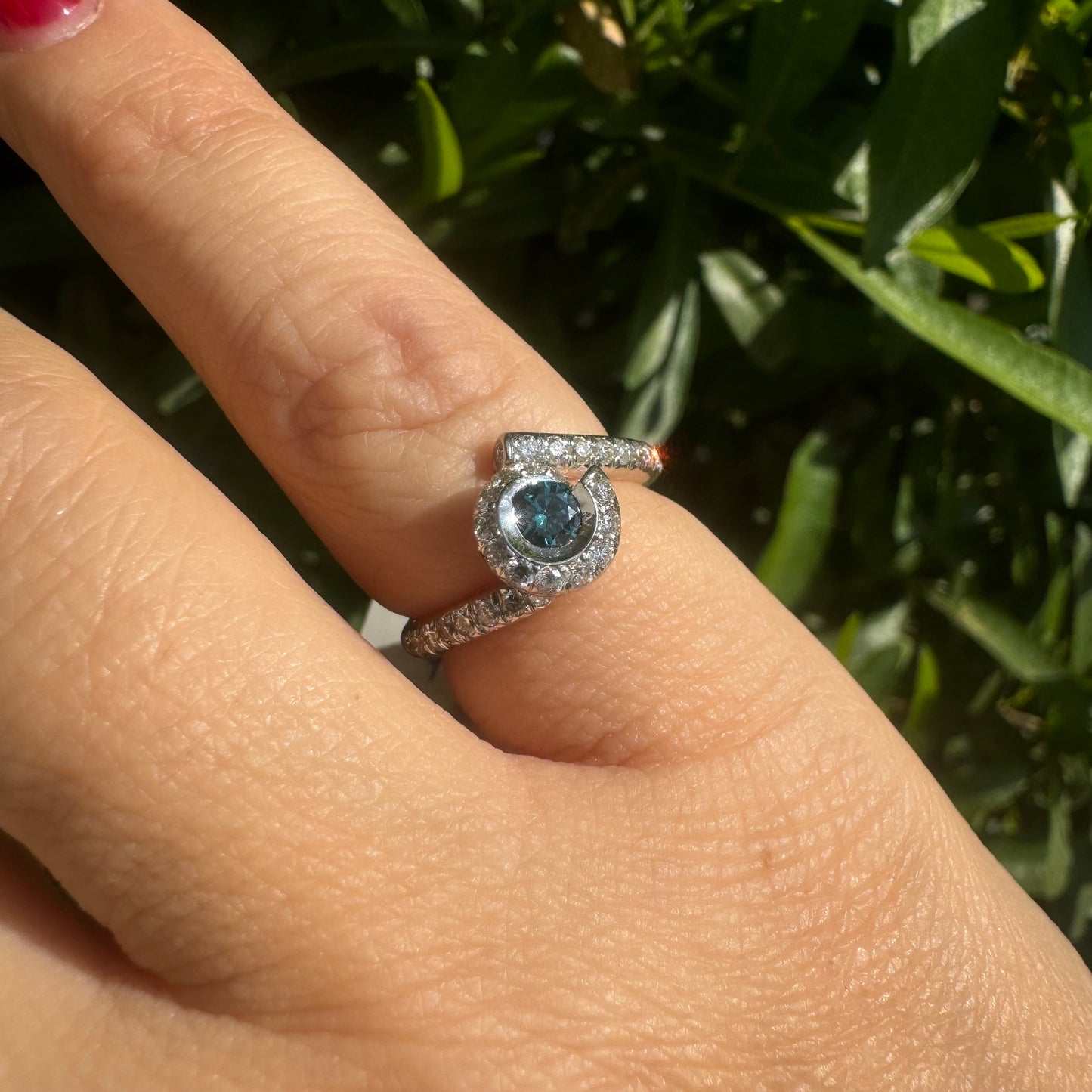 18K gold ring set with a vivid blue Diamond at its heart, embraced by a shimmering halo of white diamonds and a bold open design