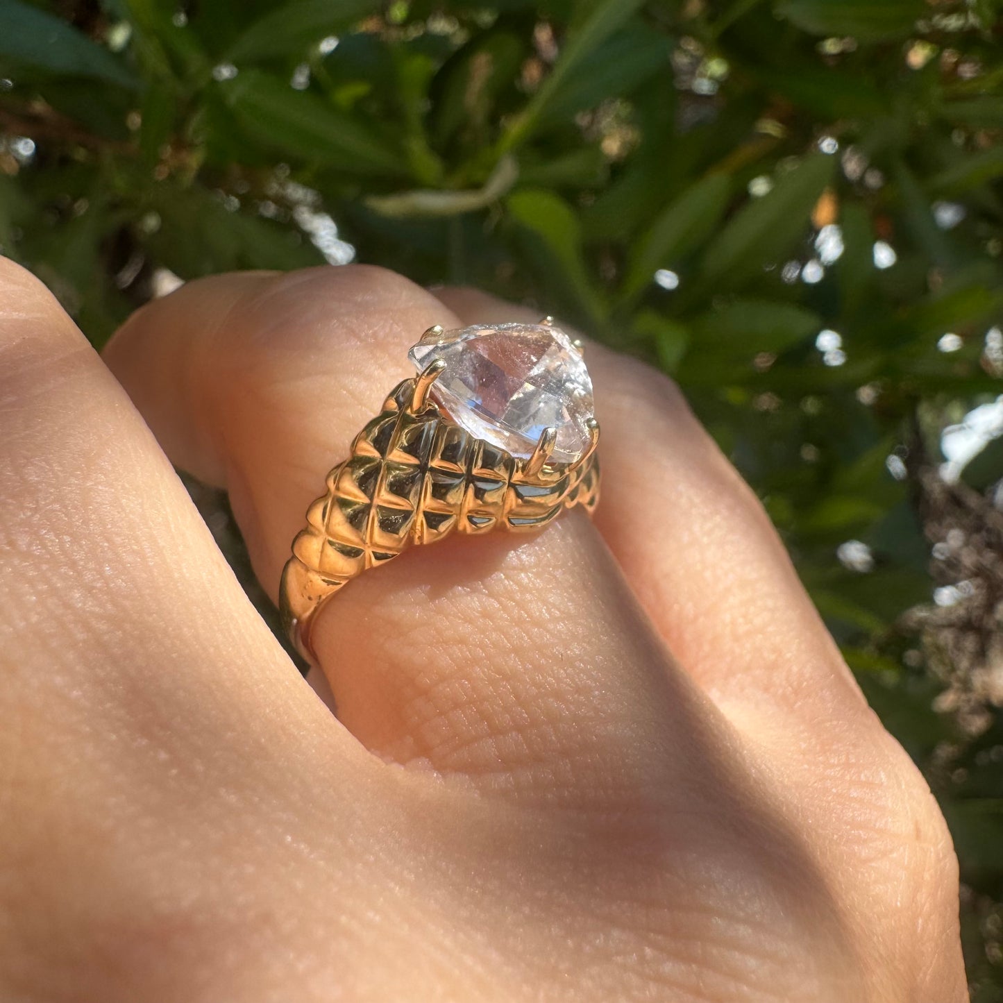 10K gold ring featuring a large, triangular-cut transparent gemstone set in a bold textured band