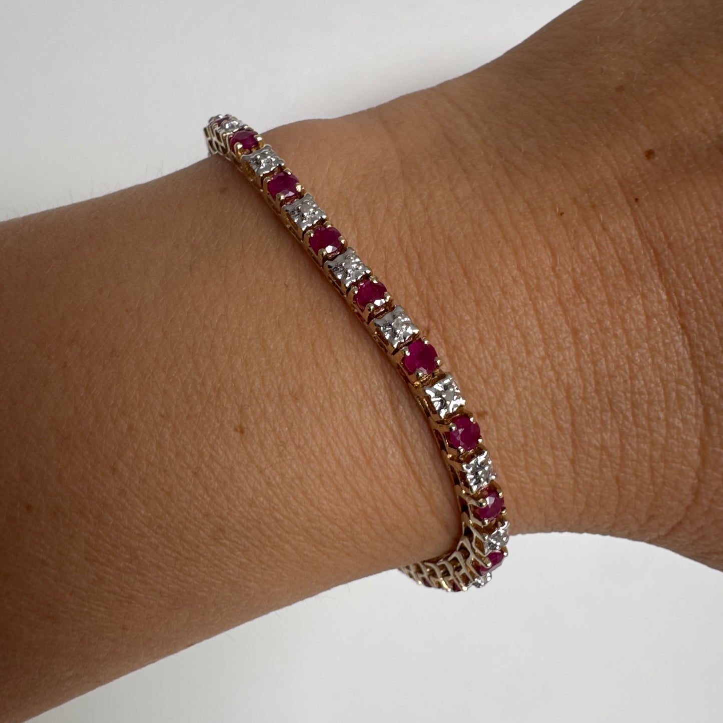 צמיד זהב צהוב 10 קראט משובץ אבני רובי בגוון אדום עמוק וביניהן יהלומים לבנים מנצנצים.