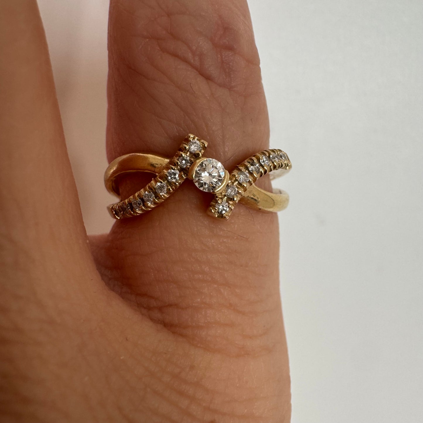 טבעת זהב 14 קראט משובצת יהלום מרכזי עגול משולב בשיבוץ יהלומים נוצצים לאורך הזרועות