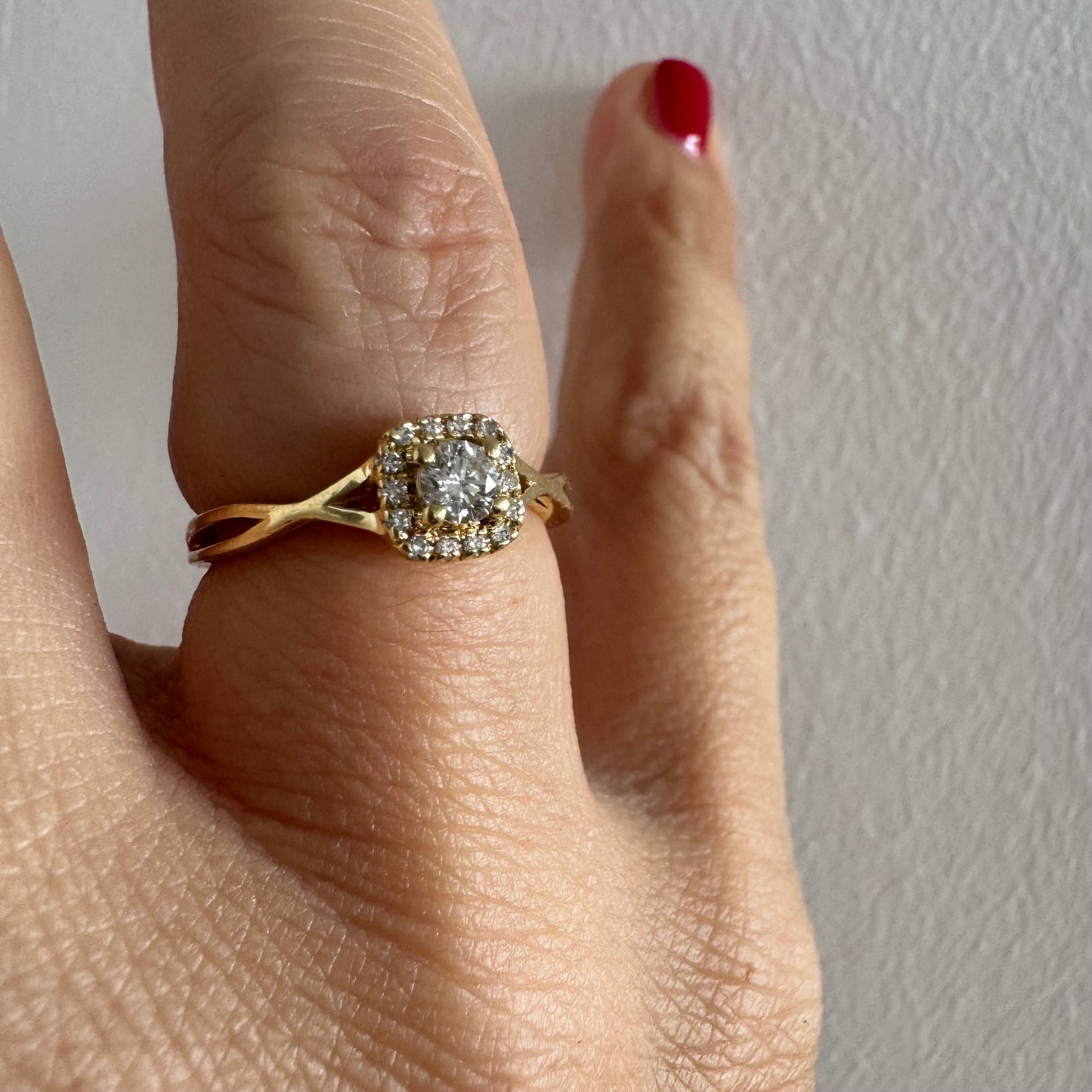 טבעת זהב 14 קראט משובצת יהלום מרכזי עגול ומבריק, מוקף הילה עדינה של יהלומים המעצימים את הברק