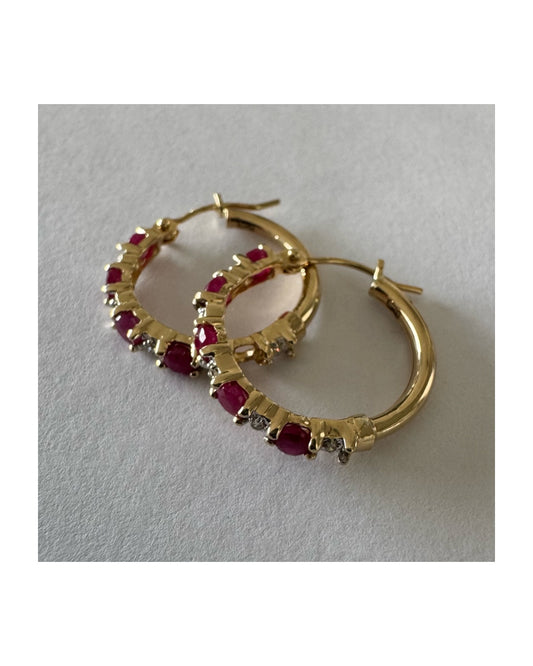 עגילי חישוק זהב צהוב 14 קראט משובצים אבני רובי בגוון אדום עמוק, בשילוב יהלומים המעניקים ברק עדין בין האבנים.