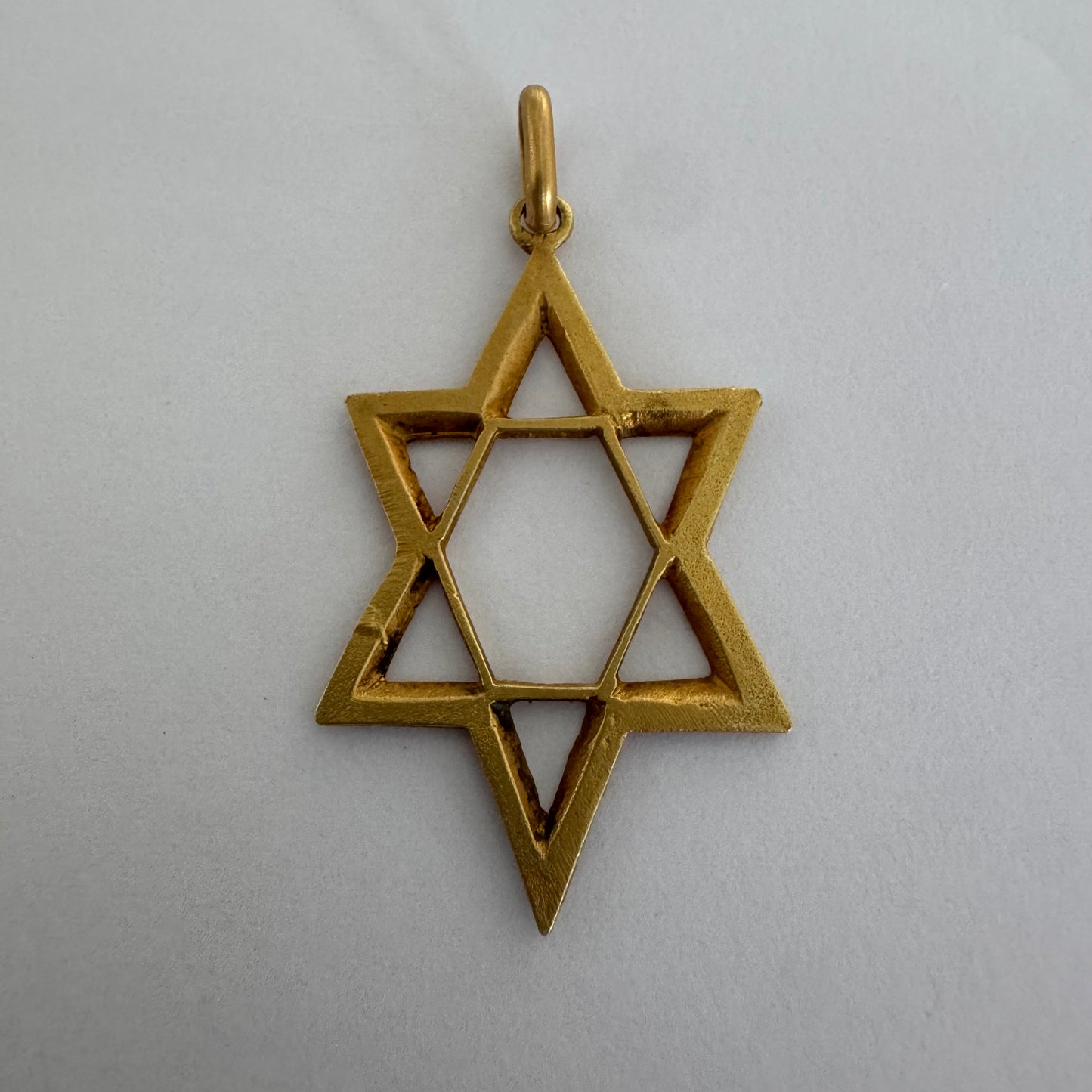 תליון מגן דוד מזהב צהוב 14 קראט בעיצוב פתוח, עם טקסטורה עדינה בשוליים המוסיפה עומק ואופי.