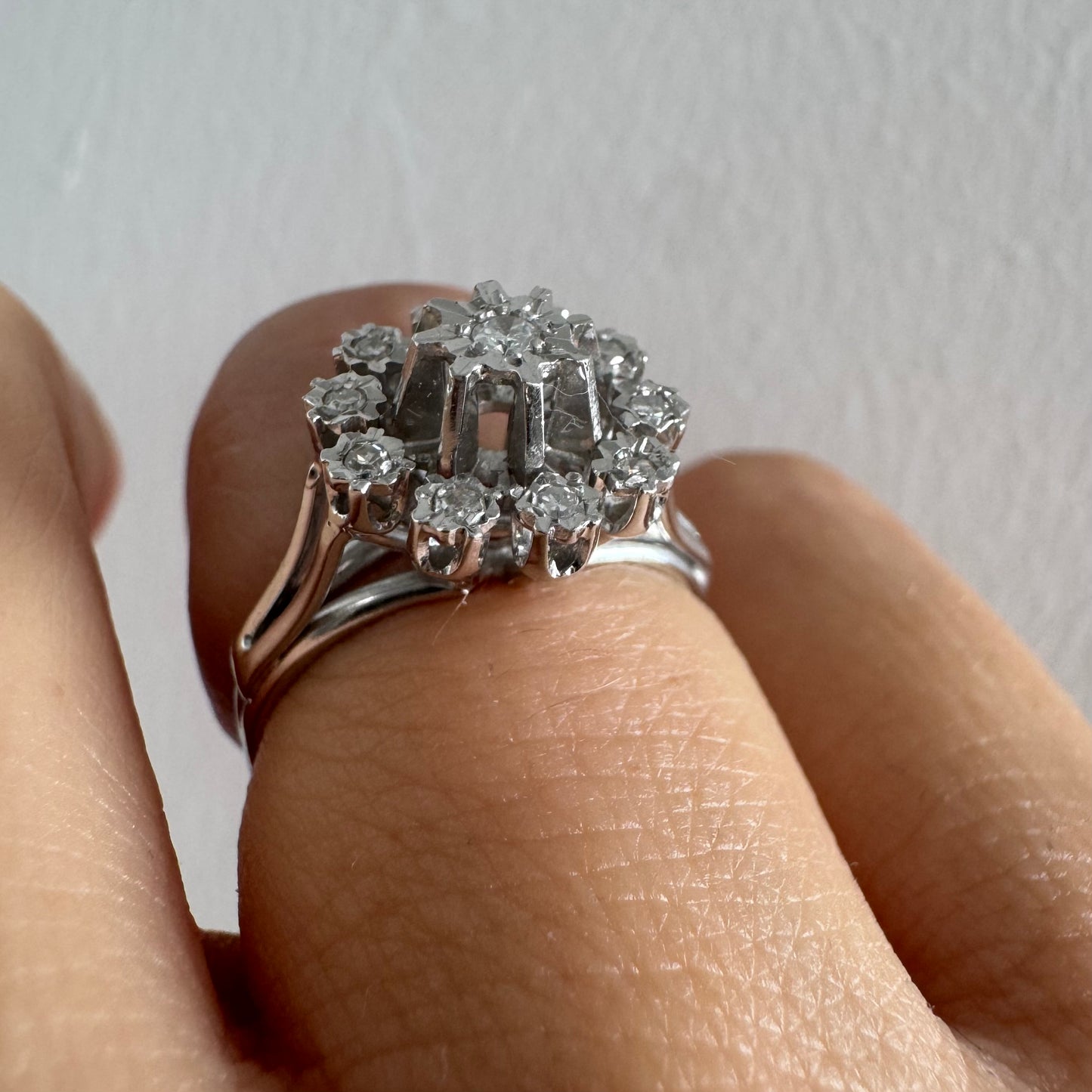 טבעת זהב 18 קראט משובצת יהלום מרכזי מוקף יהלומים נוספים בעיצוב פרח סימטרי ומרשים