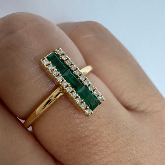 טבעת זהב 14 קראט משובצת אבני אמרלד בחיתוך באגט, מוקפות בשתי שורות של יהלומים נוצצים .