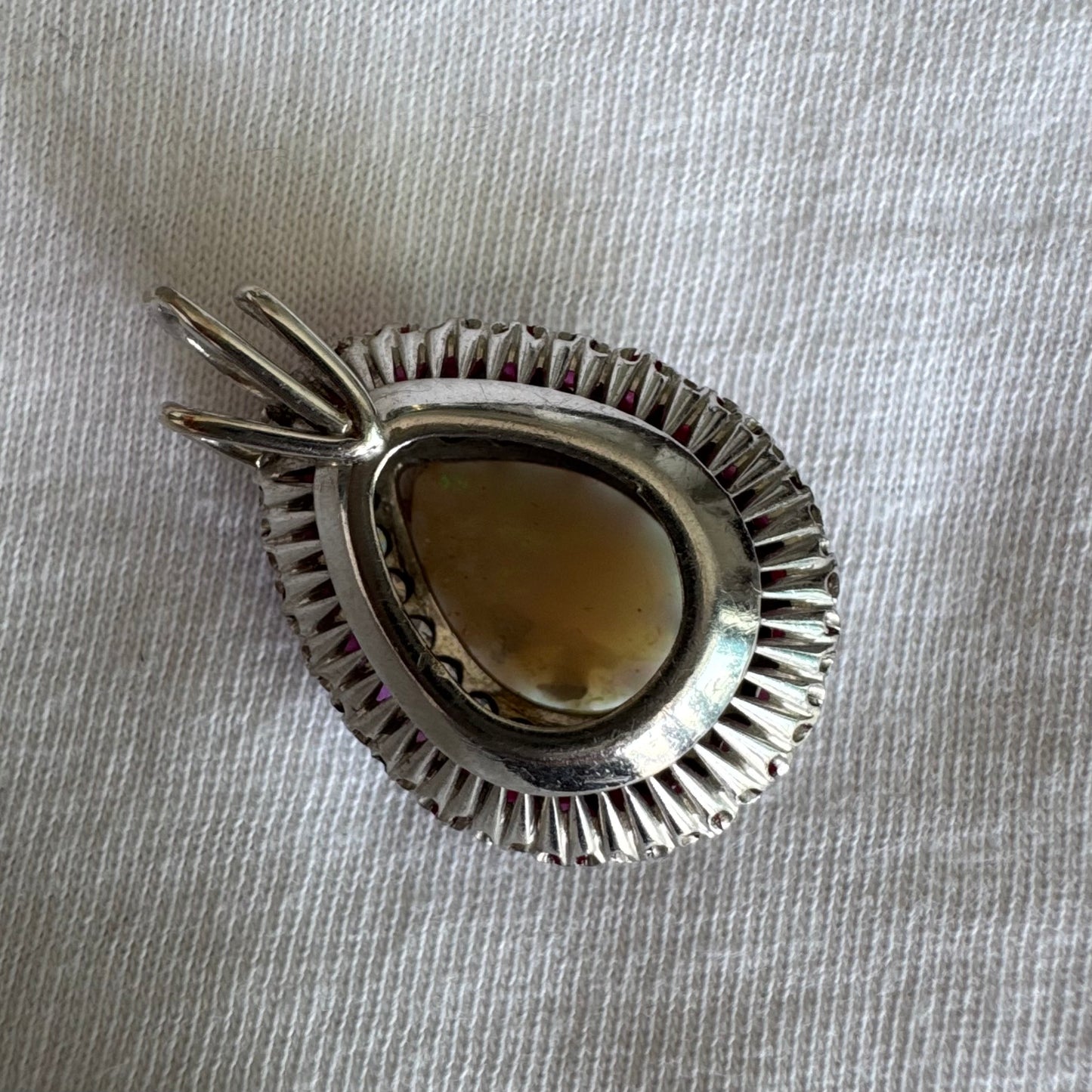 תליון זהב 14 קראט משובץ אבן אופל בחיתוך טיפה, מוקפת בשתי מסגרות של יהלומים ורובי נוצצים. 