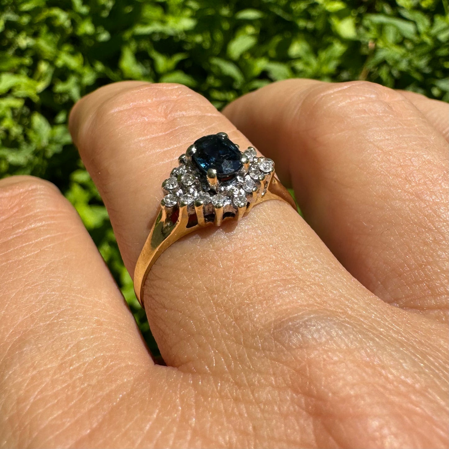 14K gold ring set with an oval blue Sapphire surrounded by sparkling Diamonds