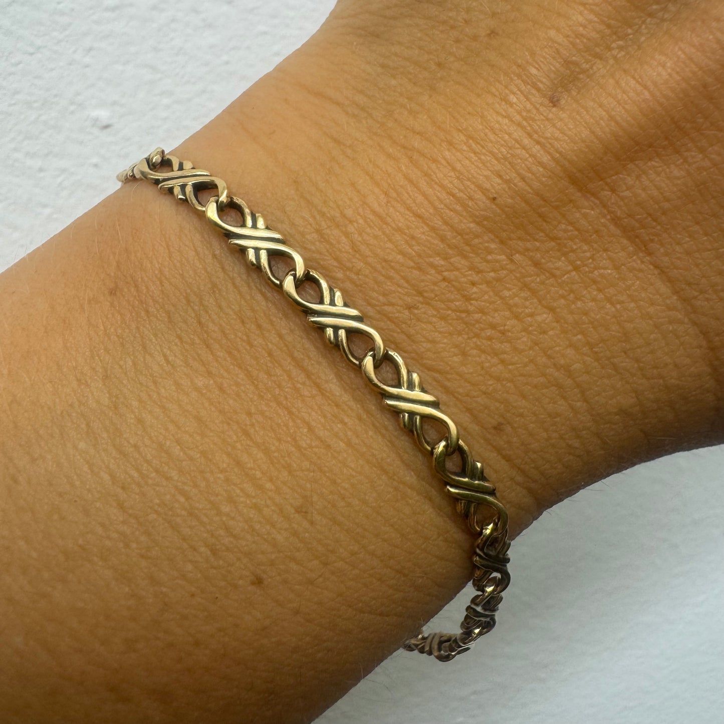 צמיד זהב צהוב 14 קראט עם חוליות שזורות בעיצוב שזירה ופיתול, וסוגר מסוג לובסטר.