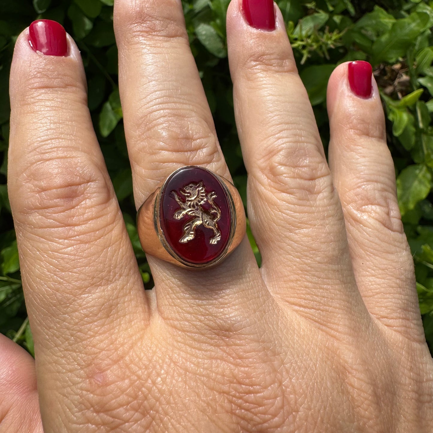 14K gold signet ring set with a smooth deep red stone set with a golden lion motif