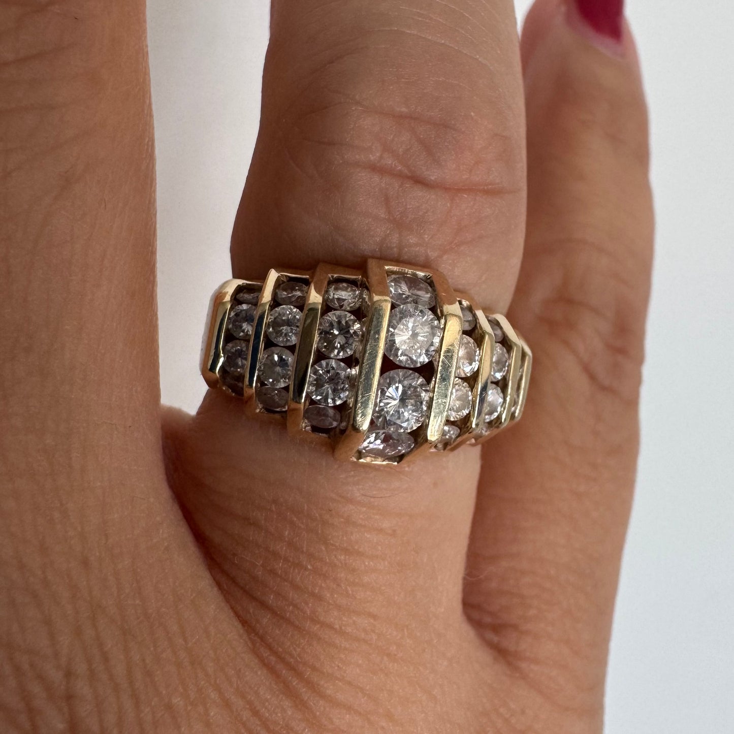 טבעת זהב צהוב 14 קראט בעיצוב רחב וגיאומטרי, משובצת יהלומים עגולים המסודרים במספר שורות מדורגות.