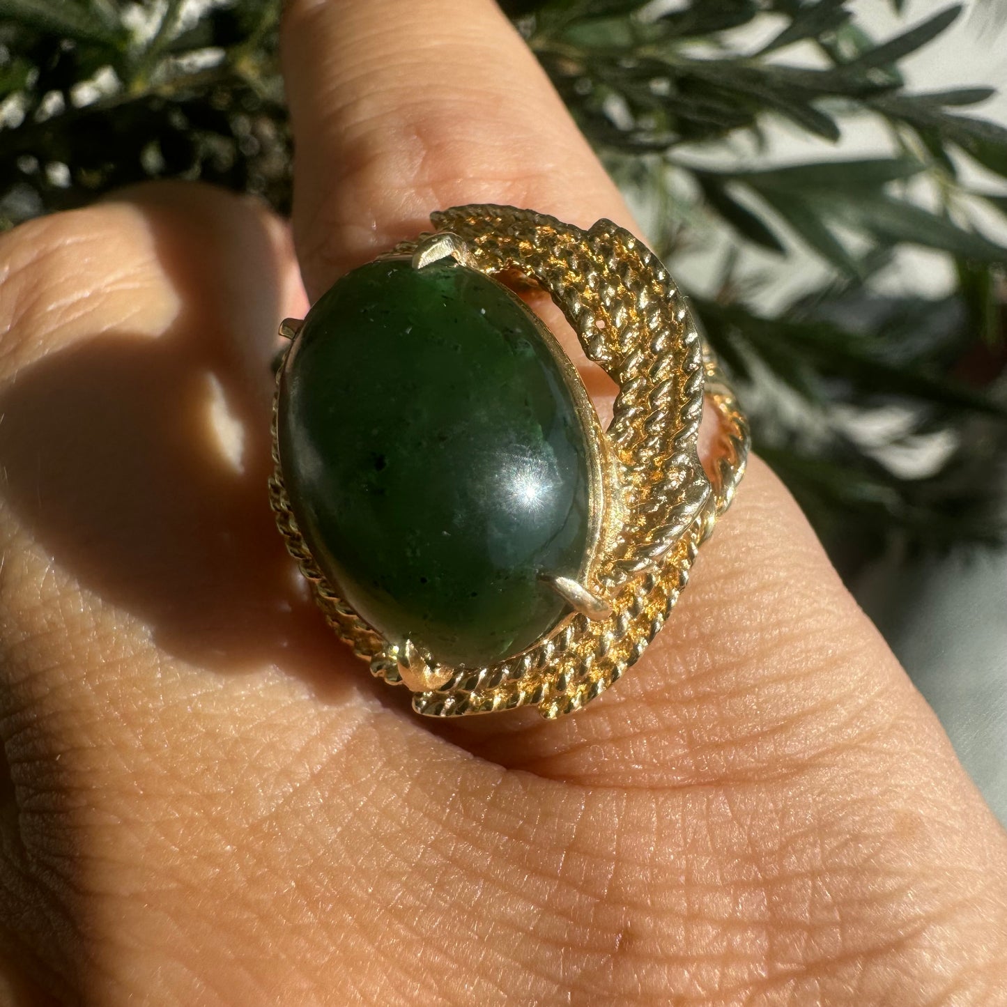14K gold ring set with a deep green Jade set in a textured gold frame.