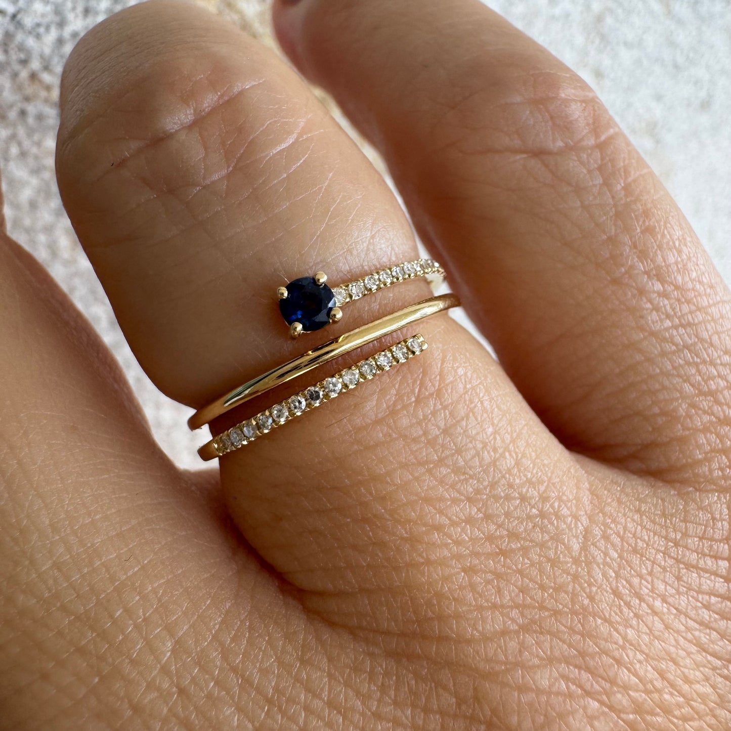 טבעת זהב צהוב 14 קראט משובצת אבן ספיר כחולה ויהלומים נוצצים בשורות עדינות.