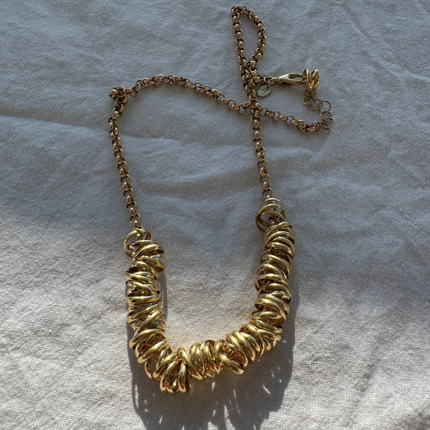 14K gold necklace featuring a series of intertwined gold rings creating a bold and sculptural design.