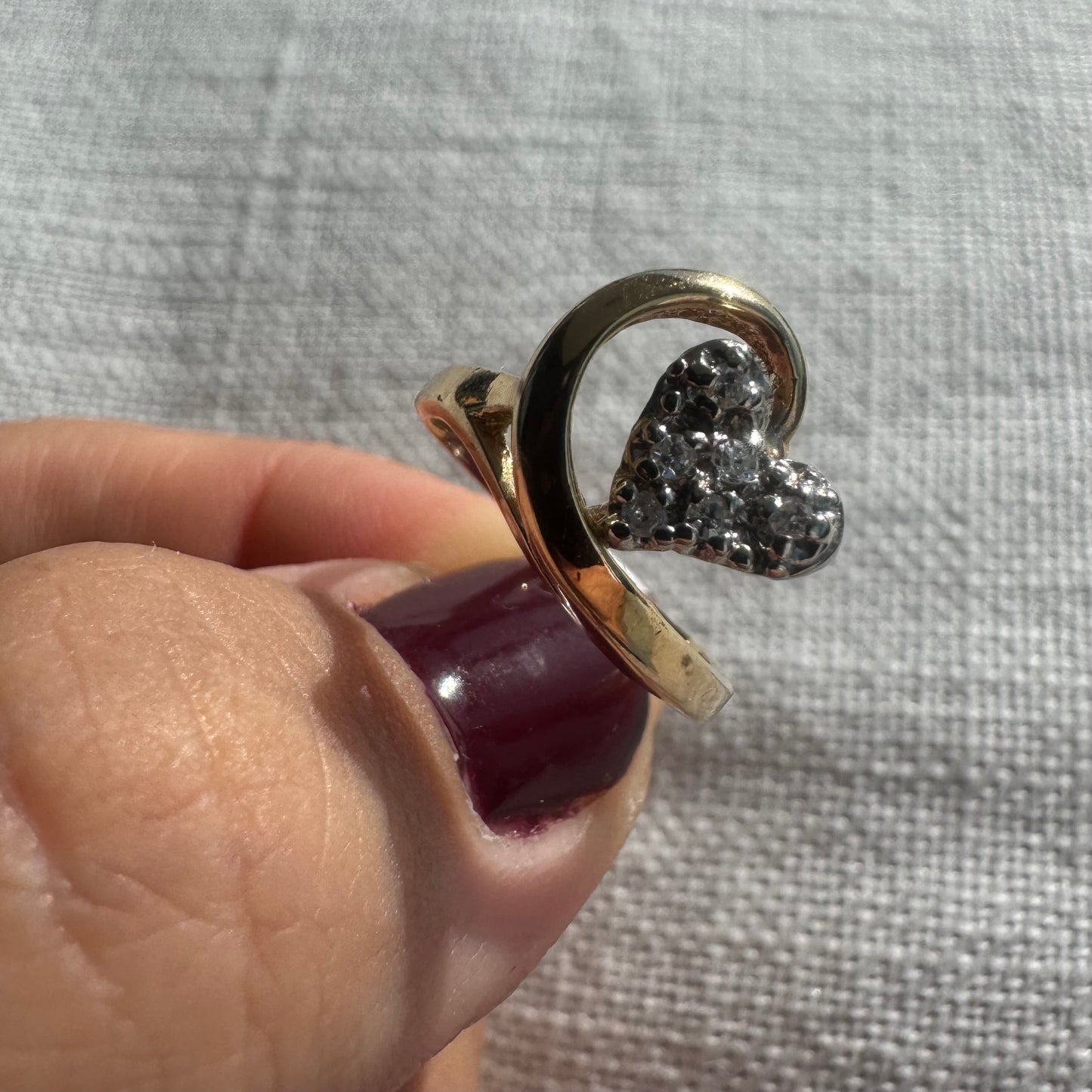 14K gold ring featuring a Diamond-studded heart embraced by a flowing golden curve.