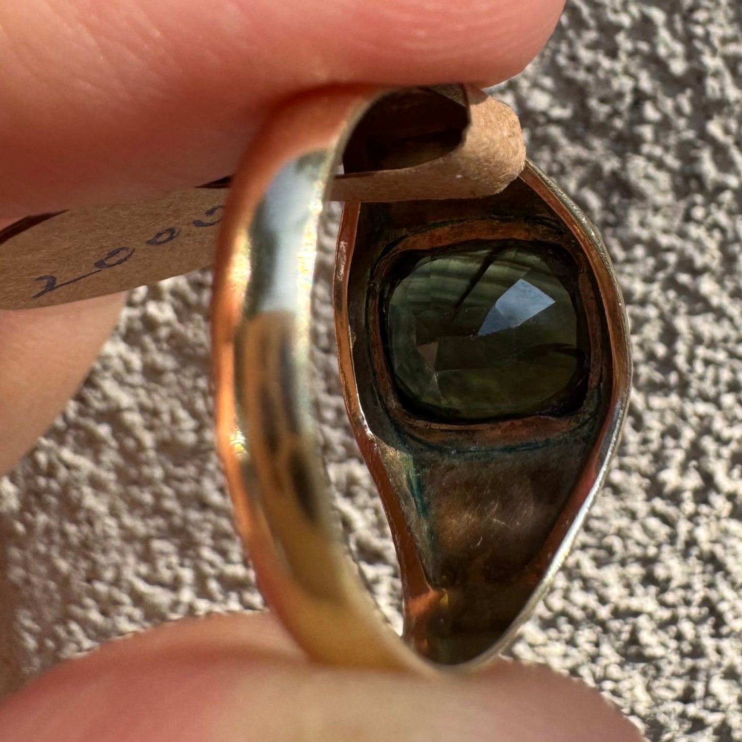 טבעת זהב 9 קראט משובצת ספיר ירוק כהה בחיתוך כרית ובתפסים עבים, בעיצוב נקי ובעל נוכחות. 