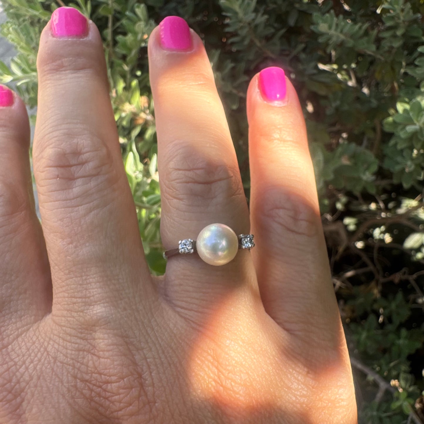 18K gold ring featuring a round Pearl at the center, flanked by two Diamonds.