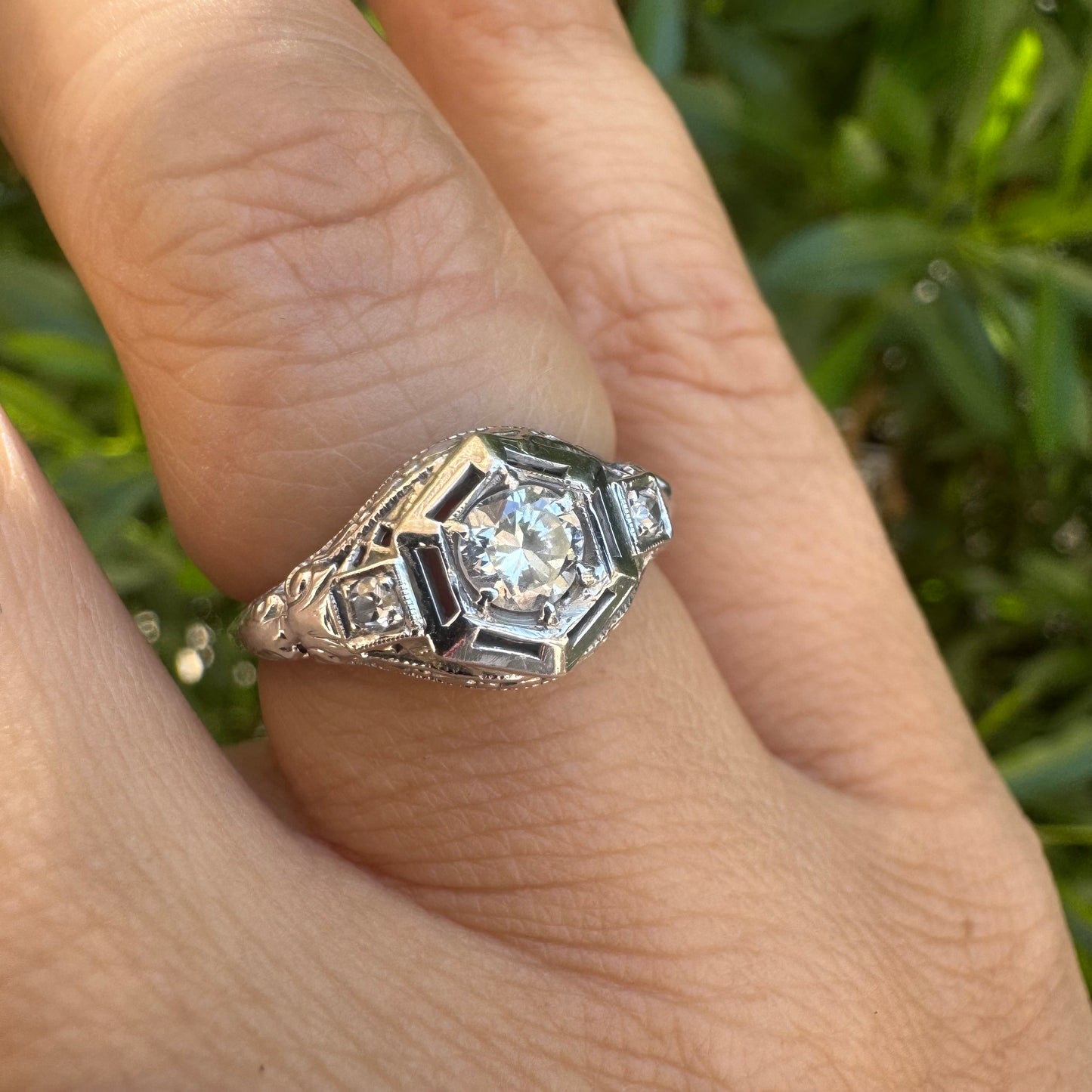 14K gold ring set with a central round diamond, framed by geometric Art Deco details and additional accent stones.