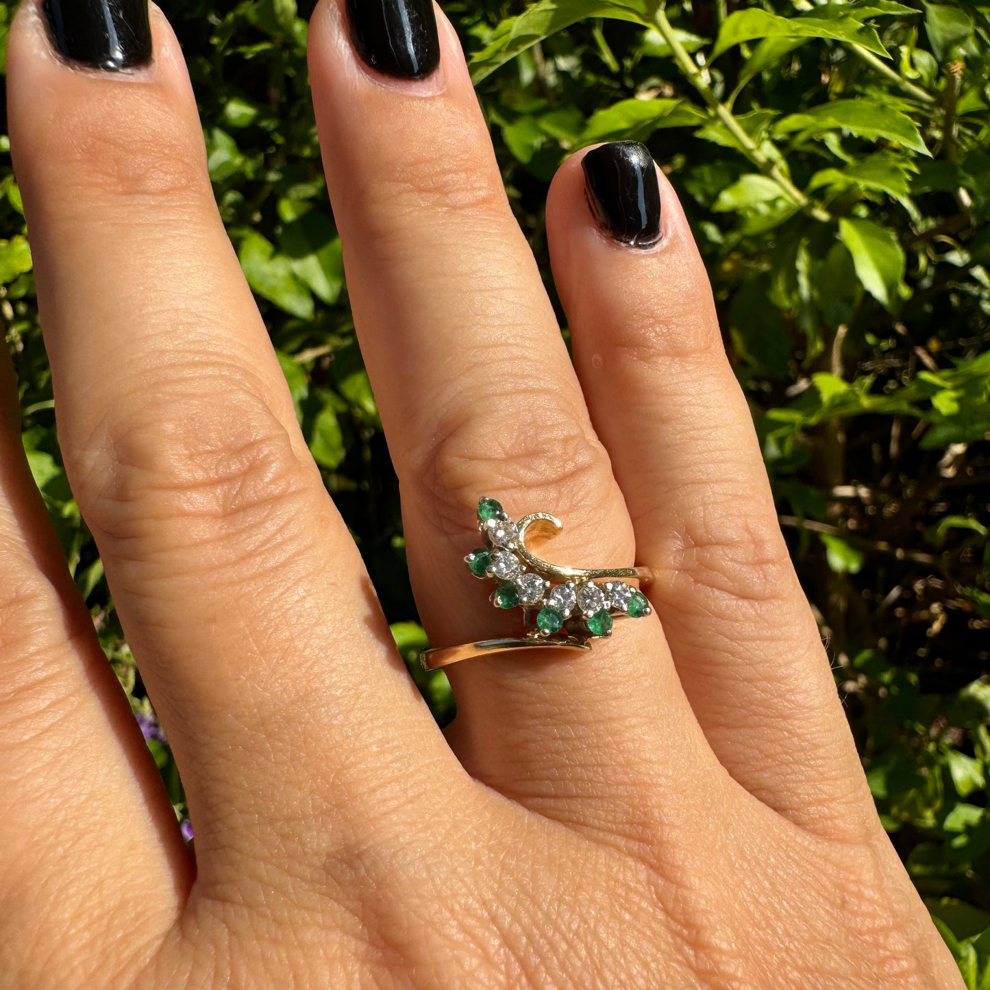 14K gold open ring featuring a delicate swirl set with Emeralds and brilliant-cut Diamonds