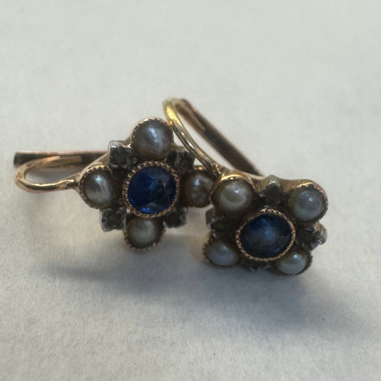 עגילי זהב 14 קראט משובצים אבן ספיר במרכז וסביבה משובצות פנינים קטנות בעיצוב פרחוני