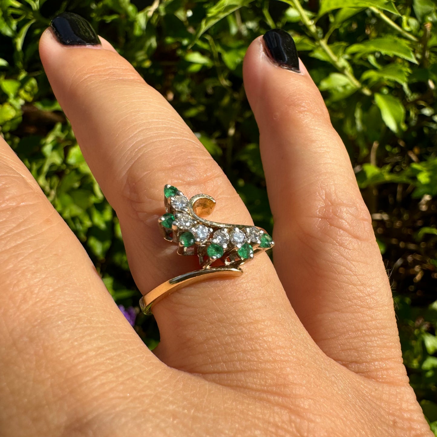 14K gold open ring featuring a delicate swirl set with Emeralds and brilliant-cut Diamonds