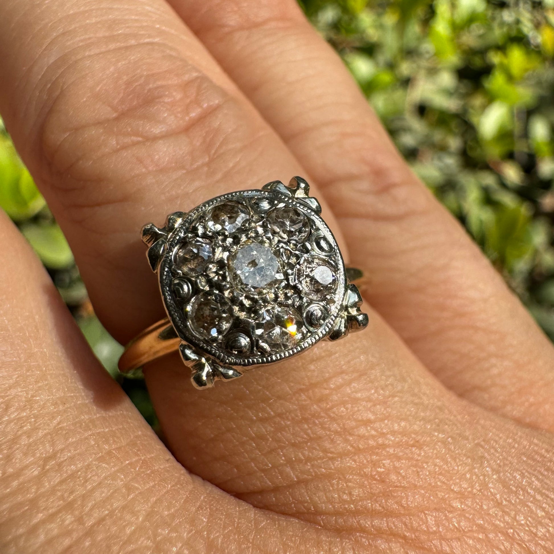 טבעת צהוב לבן 14 קראט משובצת ביהלומים בליטוש ישן (Old Cut), עם יהלום מרכזי מוקף בעיגול צפוף של יהלומים קטנים נוספים.