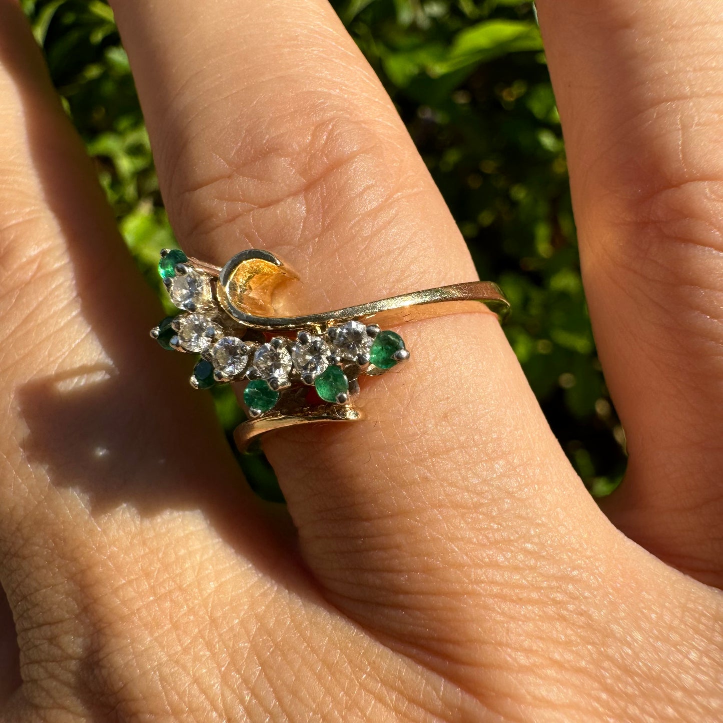 14K gold open ring featuring a delicate swirl set with Emeralds and brilliant-cut Diamonds