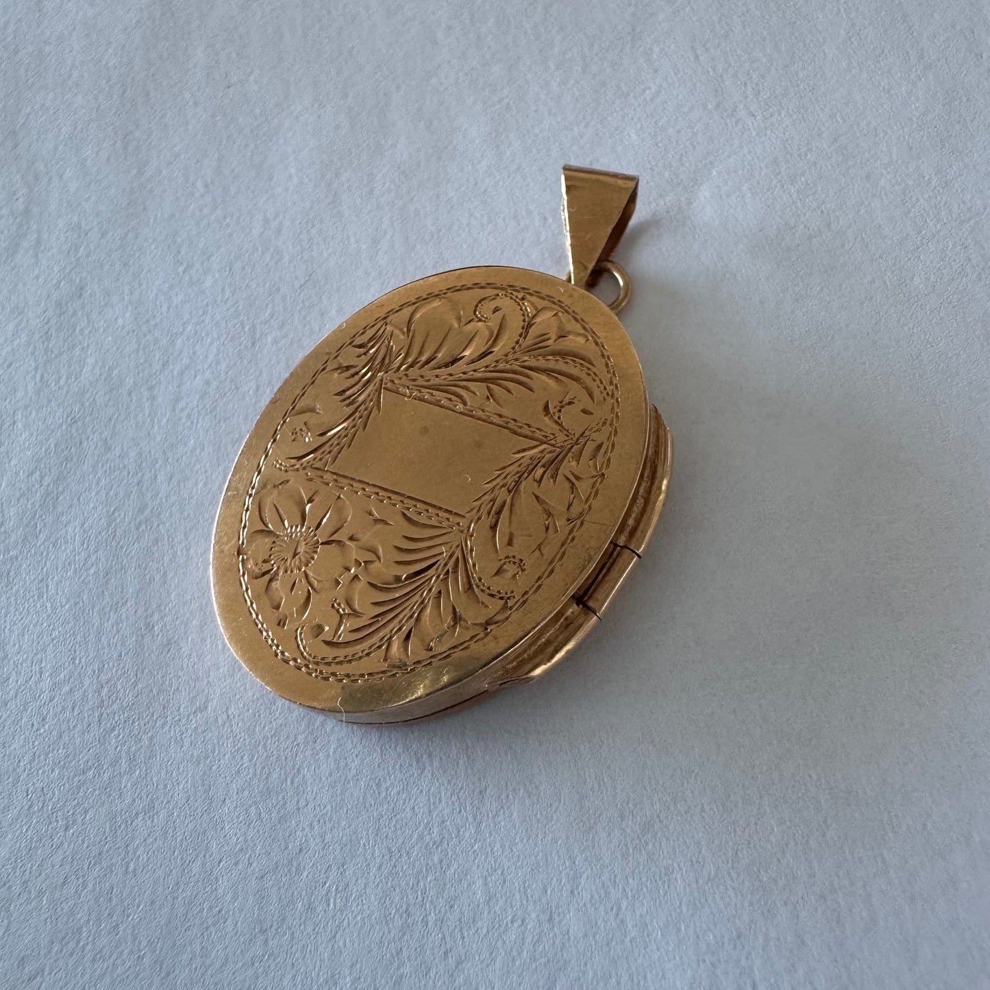 תליון לוקט זהב 14 קראט אובלי עם עיטור חריטה פרחית עדינה בעבודת יד ומסגרת אלגנטית ופתיחה לשמירת זיכרון קטן ויקר ללב.