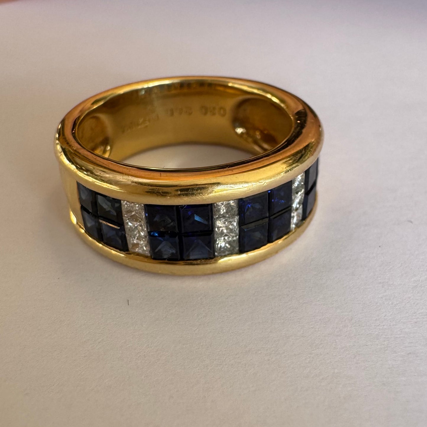 טבעת ה.שטרן זהב צהוב 18 קראט, בעיצוב רחב ומרשים. משובצת שורת אבני ספיר כחולות מרובעות בשילוב מחיצות של יהלומים לנגיעת ברק יוקרתי.