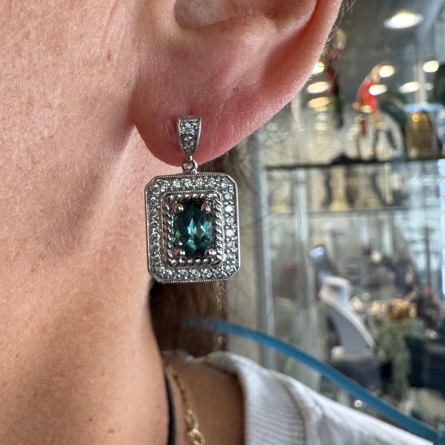 14K gold drop earrings set with emerald-cut Blue Topaz, surrounded by a halo of sparkling Diamonds