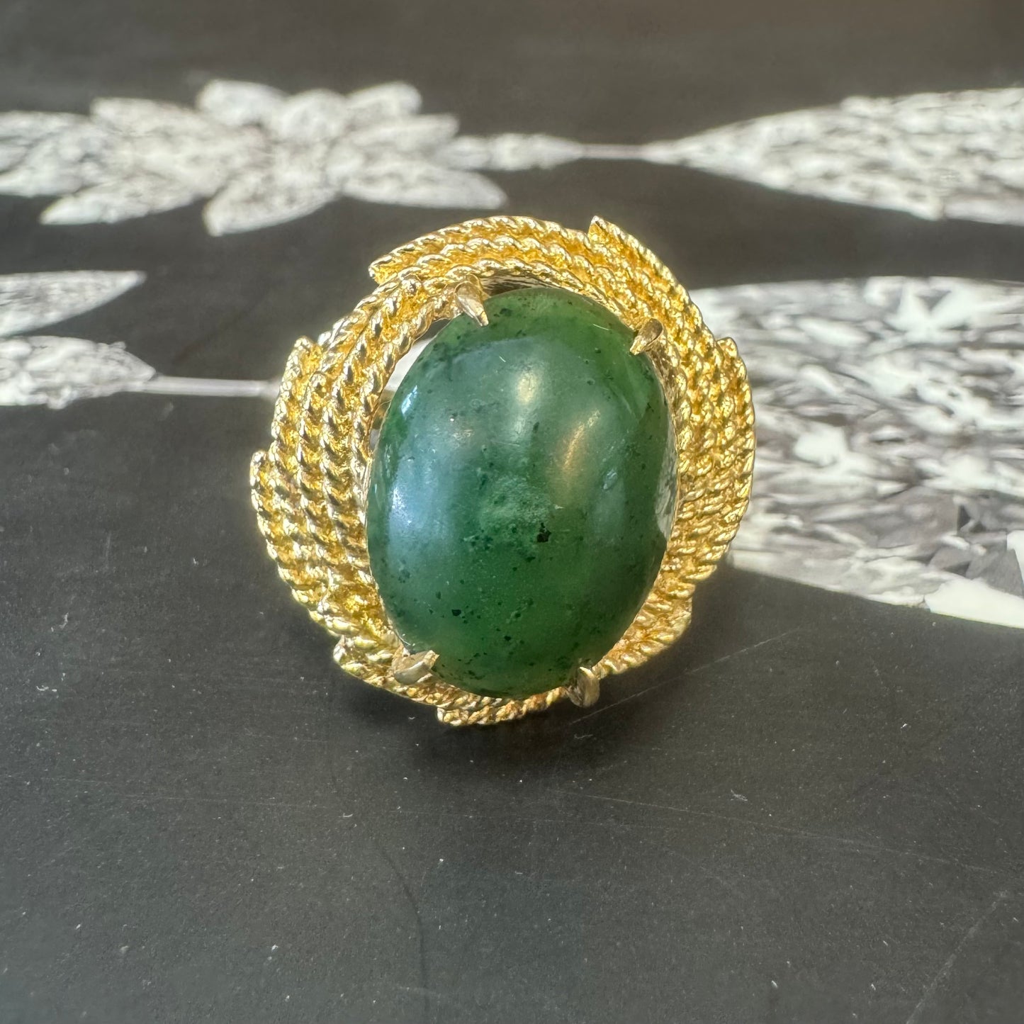 14K gold ring set with a deep green Jade set in a textured gold frame.