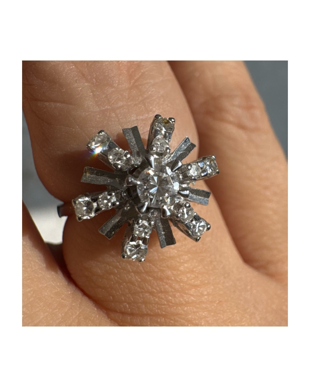 טבעת זהב לבן 18 קראט בעיצוב קרני שמש מרהיב, משובצת יהלומים הלוכדים את האור מכל כיוון. 