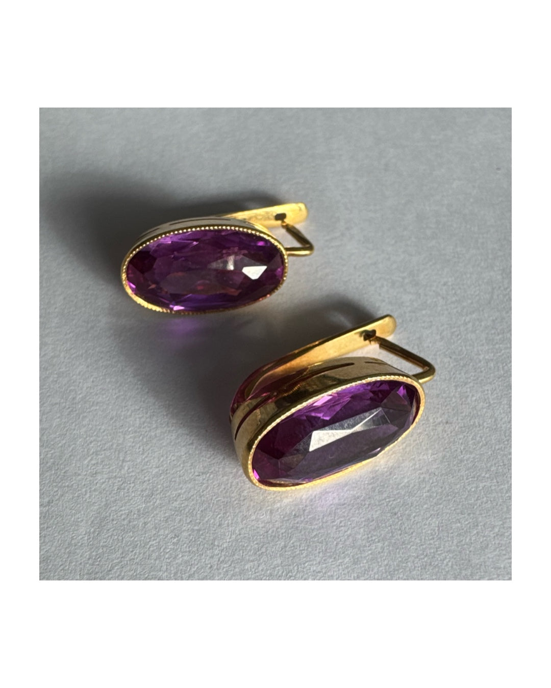 עגילי זהב צהוב 18 קראט, תלויים קצרים, משובצים באבני אמטיסט סגולות בחיתוך אובלי עמוק.