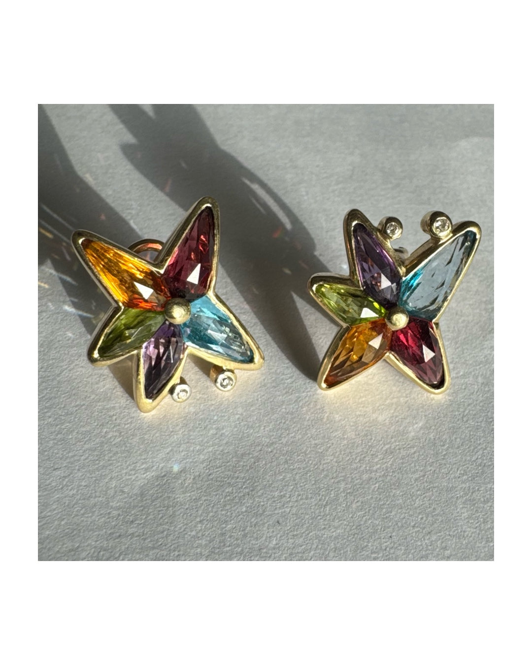 עגילי זהב צהוב 14 קראט בעיצוב כוכב משובצים אבני חן צבעוניות בחיתוך מרקיז, היוצרות מראה של כוכב זוהר מלא חיים.